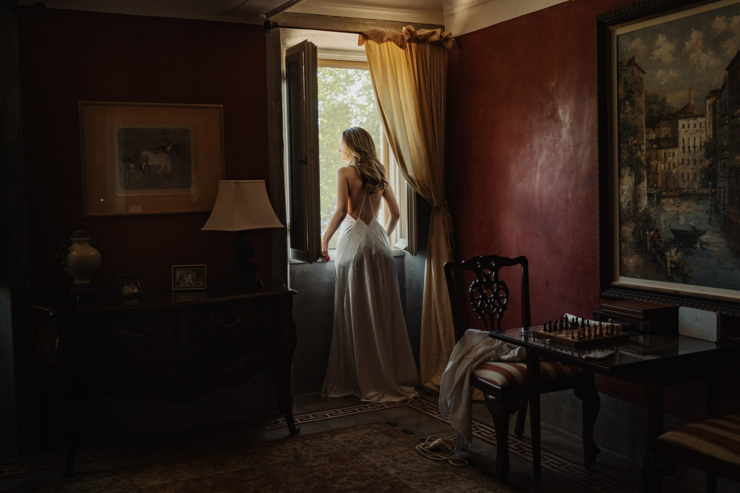 Bride looks out from an Italian villa from a window