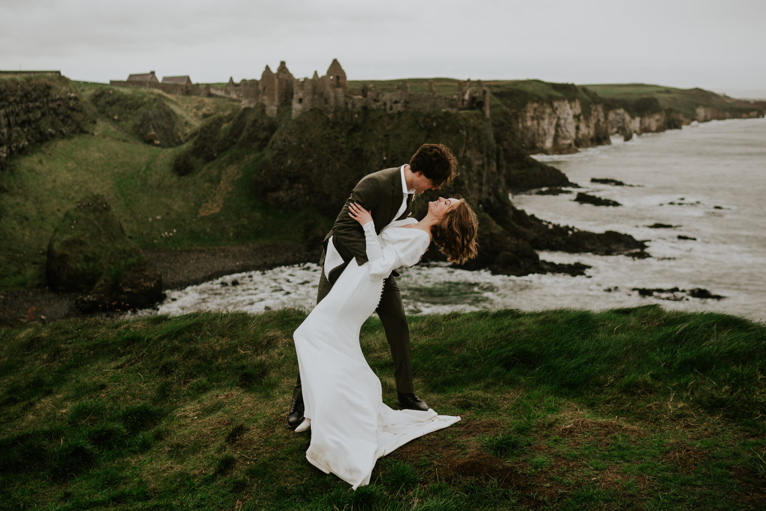 couple overlooking dunluce castle a dramatic backdrop