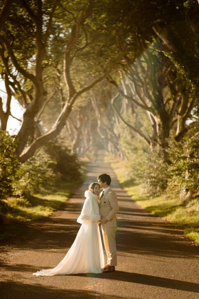 A couple at The Dark Hedges in Ireland at sunrise